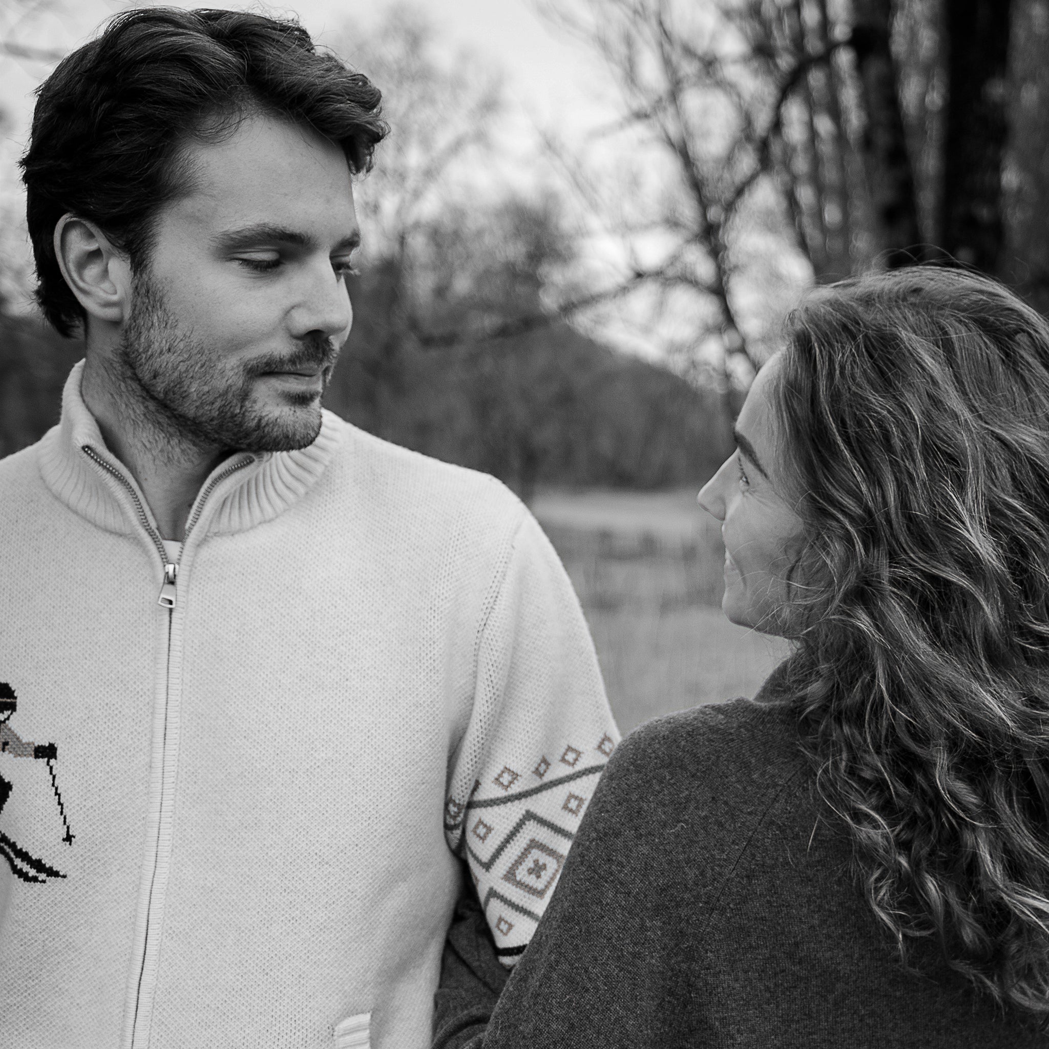 Black and white photo of a man and woman facing each other outdoors.
