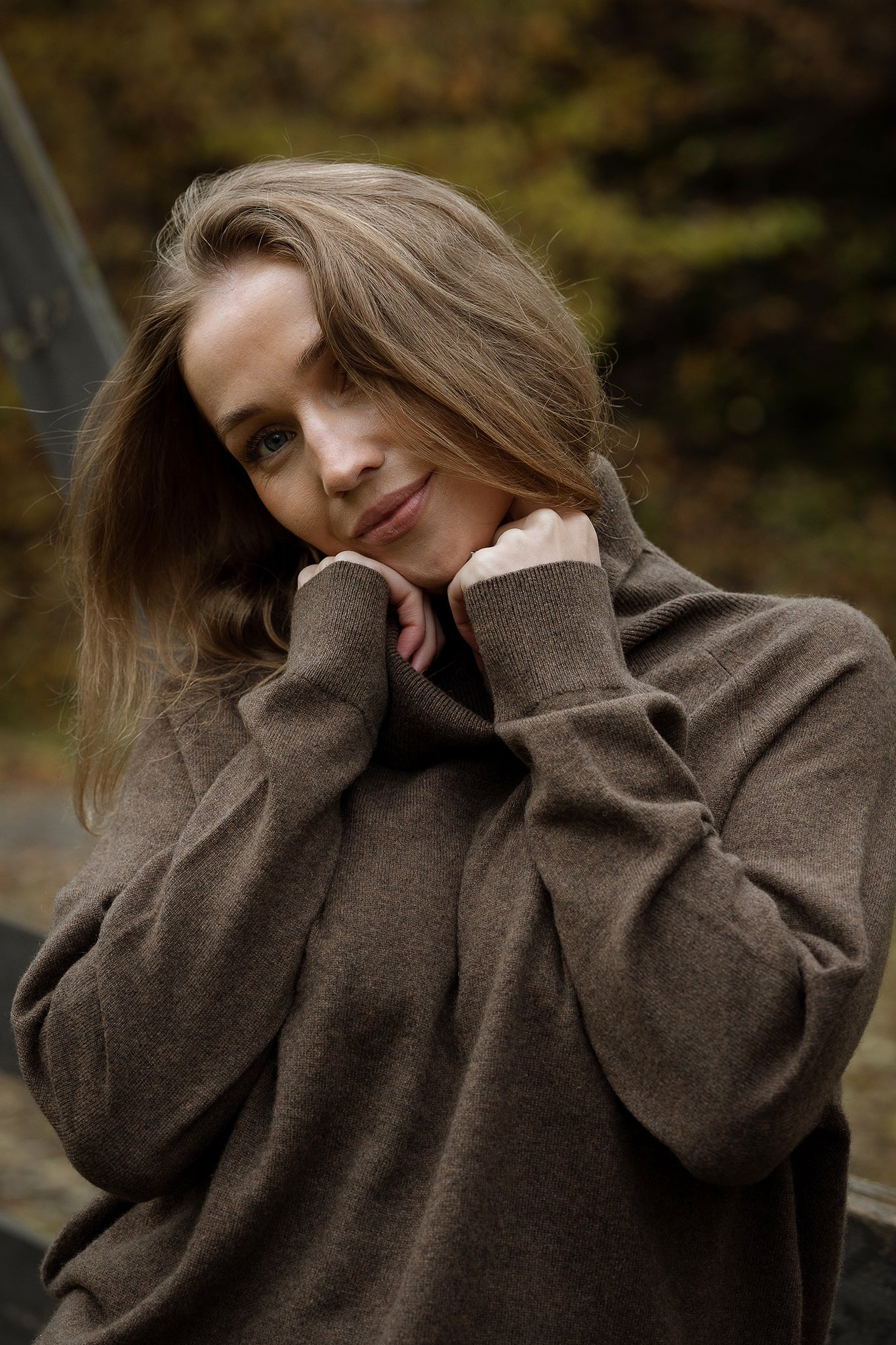 Woman wearing a brown coat with a blurred natural background